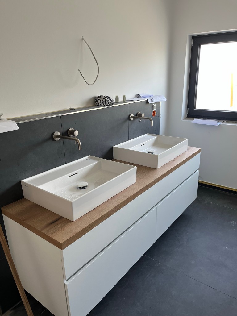 Doppelwaschtisch mit Holzplatte und wandmontierten Armaturen