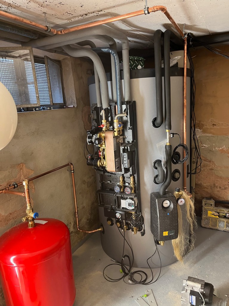Warmwasserspeicher mit Frischwasserstation und Leitungsnetz im Keller